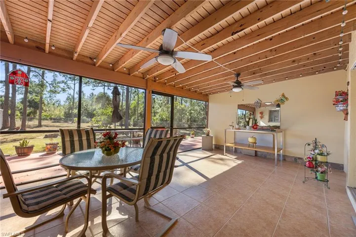 Sunroom / solarium featuring a wooden ceiling with exposed beams and tile patterned floors