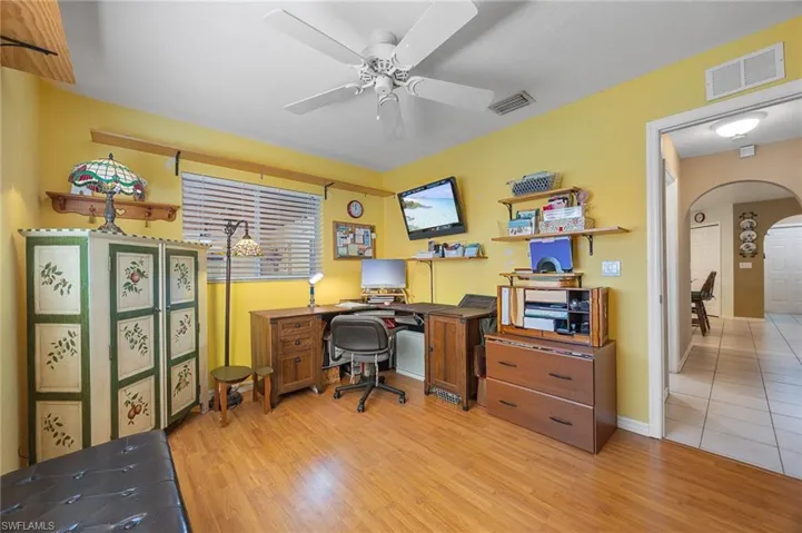 Office featuring arched walkways, light wood-type flooring, and ceiling fan