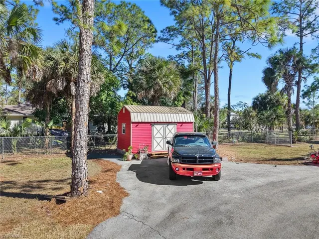 View of parking with a fenced backyard and a shed