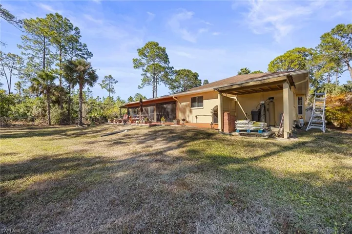Rear view of property featuring stucco siding, a sunroom, and a lawn