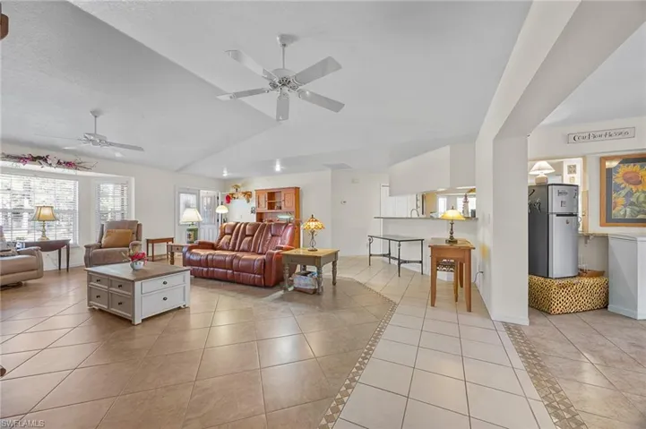 Living area featuring light tile patterned floors, a ceiling fan, and lofted ceiling