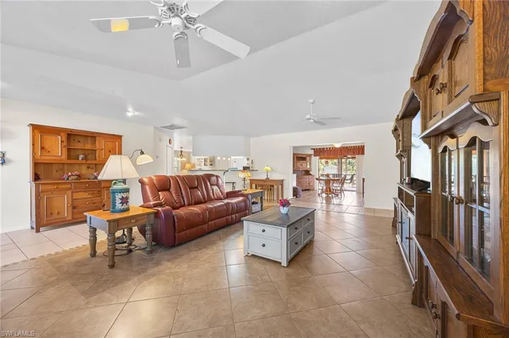 Living room with a ceiling fan, light tile patterned flooring, and vaulted ceiling