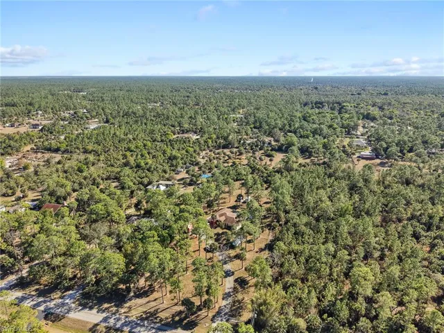 Aerial view of property and surrounding area featuring a forest