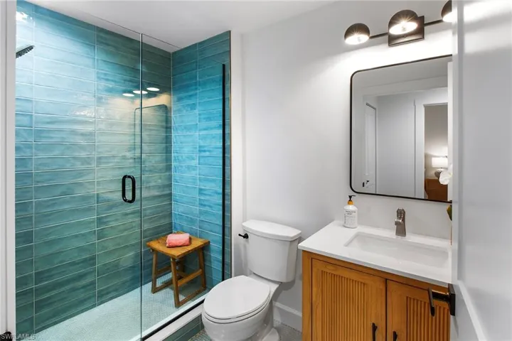 Bathroom featuring baseboards, vanity, toilet, and a shower stall
