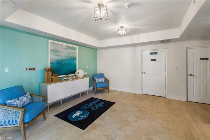 Sitting room featuring baseboards, a raised ceiling, a notable chandelier, and wood finished floors