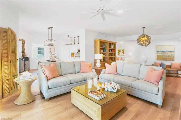 Living room featuring light wood-style flooring and ceiling fan with notable chandelier