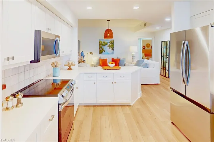 Kitchen with open floor plan, stainless steel appliances, a peninsula, and light wood-style flooring