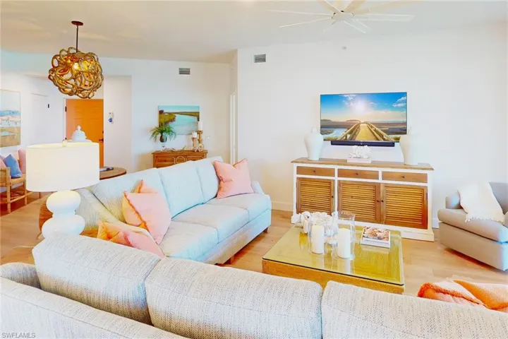 Living area with a ceiling fan, visible vents, and wood finished floors