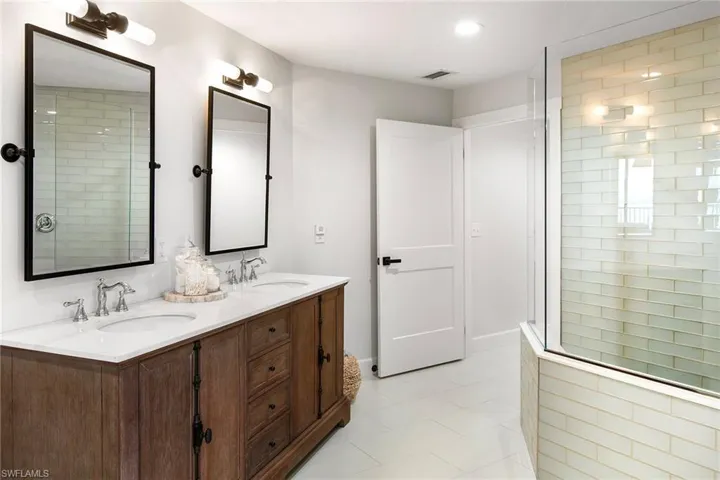 Bathroom featuring double vanity, tiled shower, visible vents, and a sink
