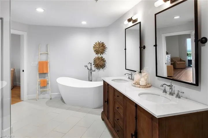 Bathroom featuring a sink, a soaking tub, double vanity, and recessed lighting