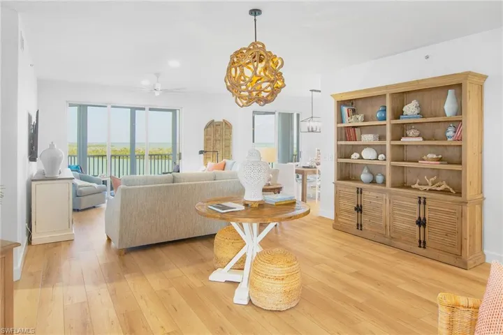 Living area with ceiling fan with notable chandelier and light wood-type flooring