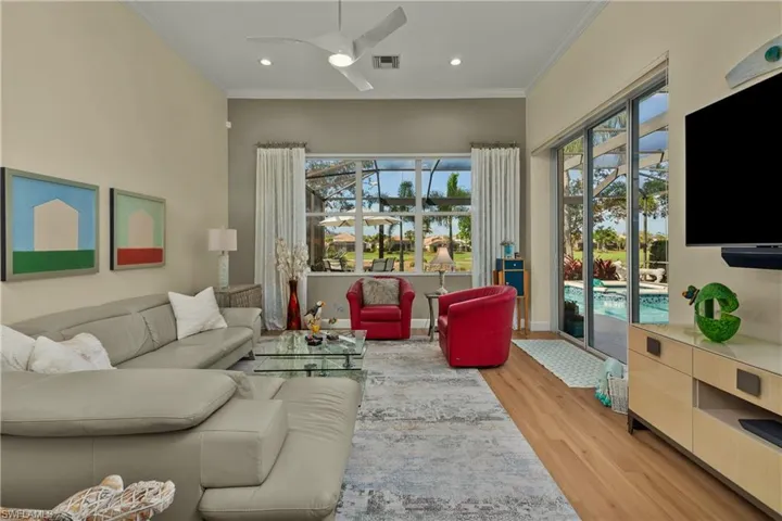 Living room with crown molding, ceiling fan, and light hardwood / wood-style floors