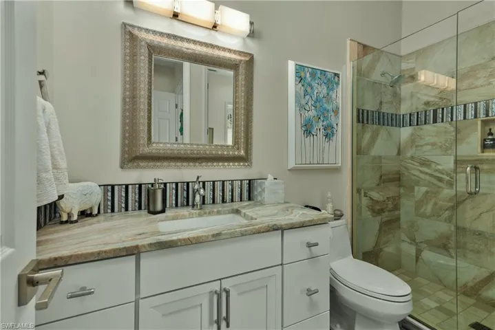 Bathroom featuring vanity, toilet, and a shower with door
