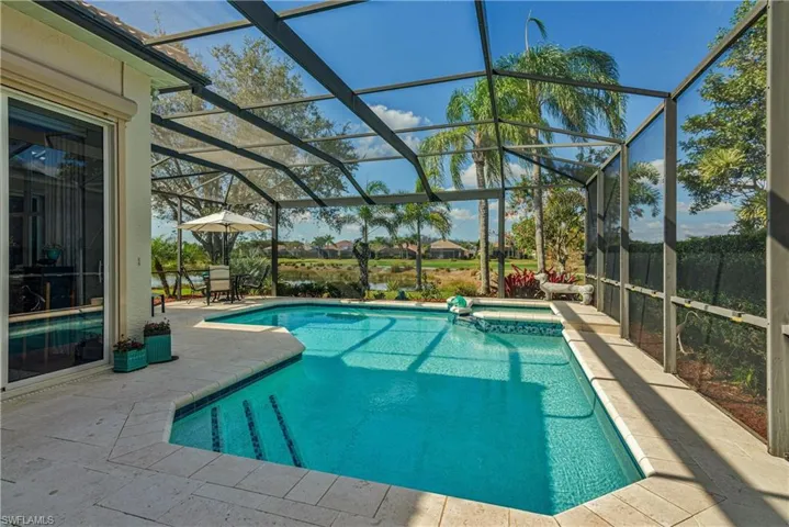 View of swimming pool with glass enclosure and a patio area
