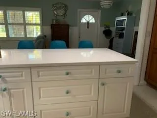 Kitchen with white cabinets, light countertops, and a wainscoted wall