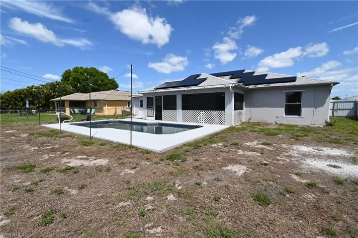 Back of house featuring roof mounted solar panels, a sunroom, a fenced backyard, a patio, and stucco siding