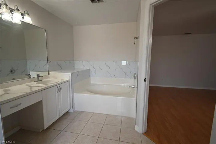 Bathroom featuring a bath, vanity, and light tile patterned floors