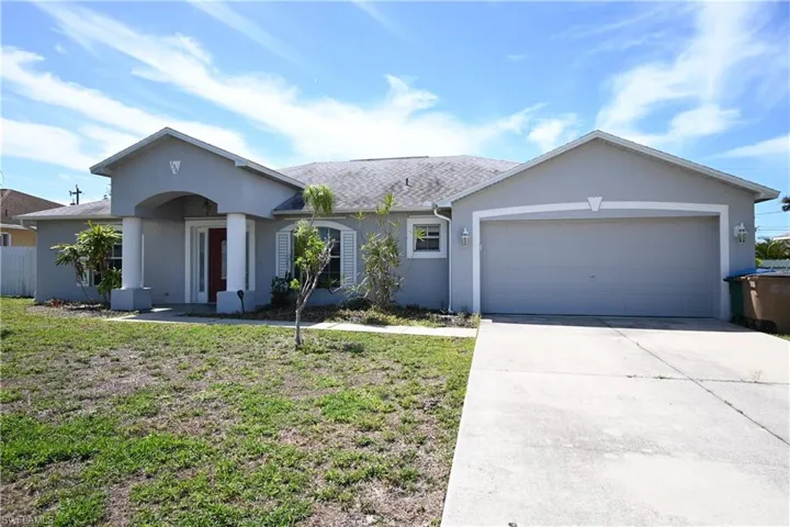 Single story home featuring a garage, stucco siding, driveway, and a front yard