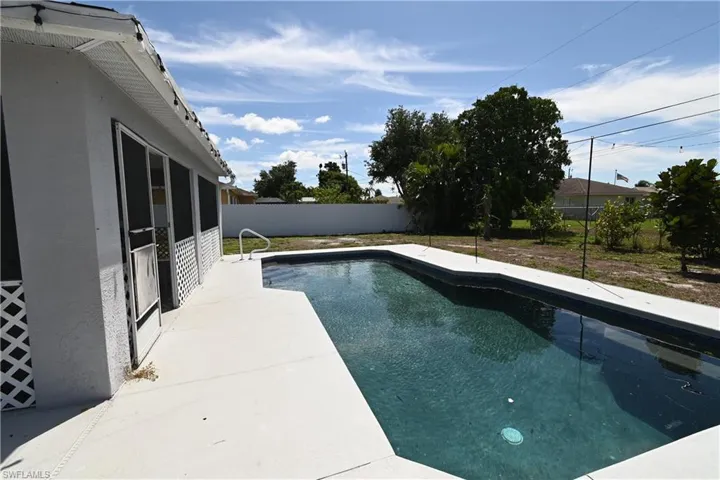 View of swimming pool with a fenced backyard, patio surround, and a sunroom