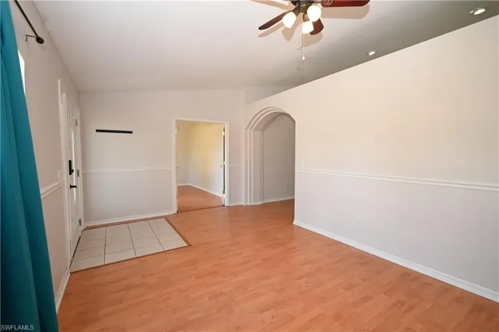 Unfurnished room with ceiling fan, arched walkways, and light wood-style floors