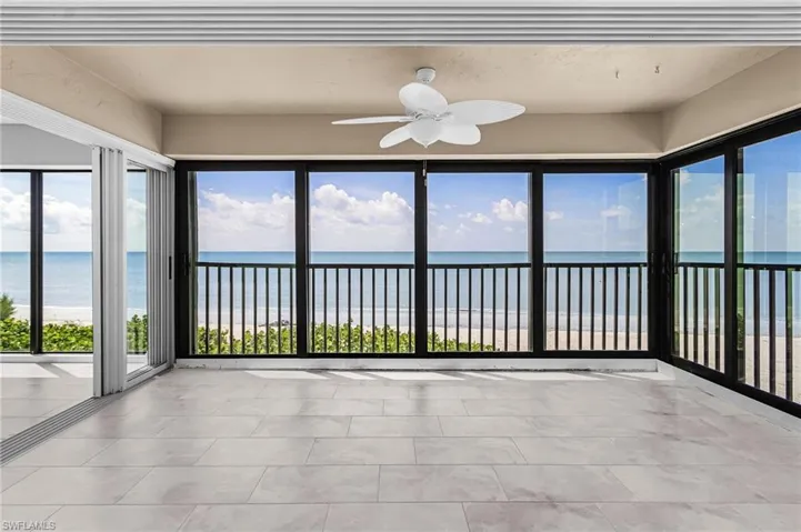 Unfurnished sunroom featuring view of water and beach, healthy amount of natural light, and tile patterned flooring