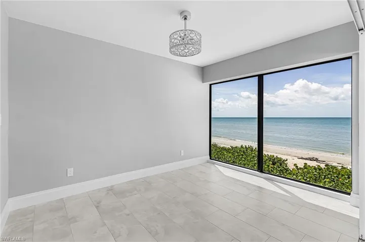 Spare room featuring view of water and beach and baseboards