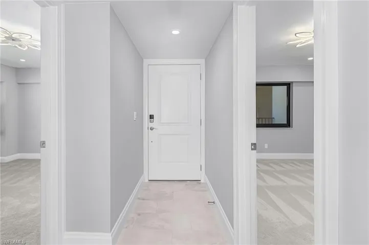 Corridor with light carpet, recessed lighting, and light tile patterned floors
