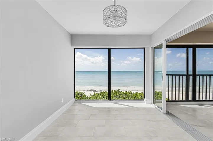 Spare room with view of water and beach and light tile patterned flooring