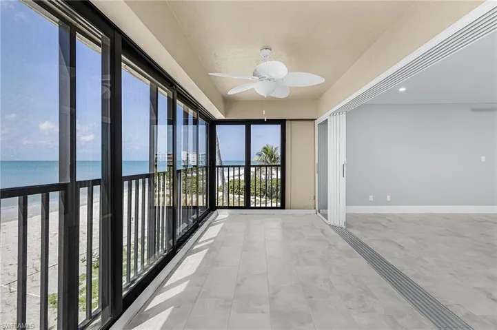 Unfurnished sunroom featuring view of water and beach and baseboards