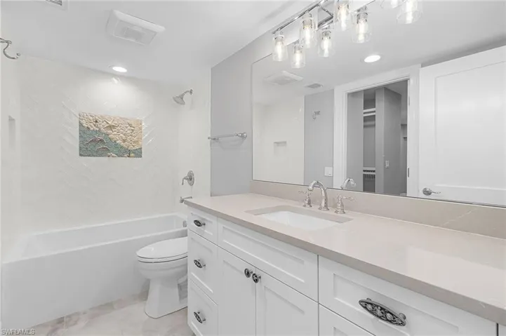 Full bath featuring shower / bath combination, vanity, a spacious closet, light tile patterned floors, and recessed lighting