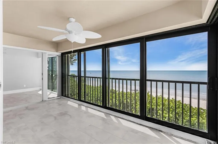 Unfurnished sunroom featuring view of water and beach and tile patterned floors