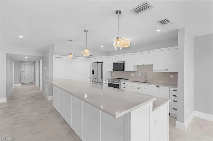Kitchen featuring white cabinetry, appliances with stainless steel finishes, hanging light fixtures, a spacious island, and recessed lighting