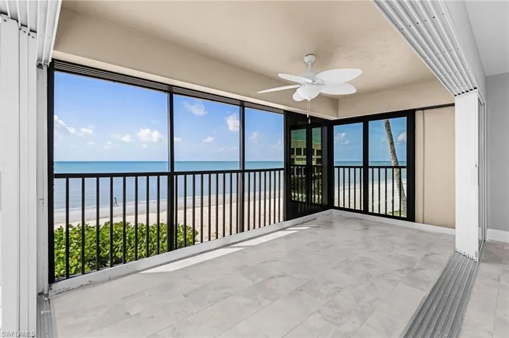 Unfurnished sunroom featuring view of water and beach