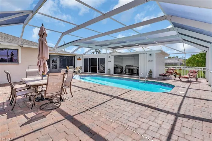 Pool with area for grilling, a patio area, glass enclosure, and outdoor dining area