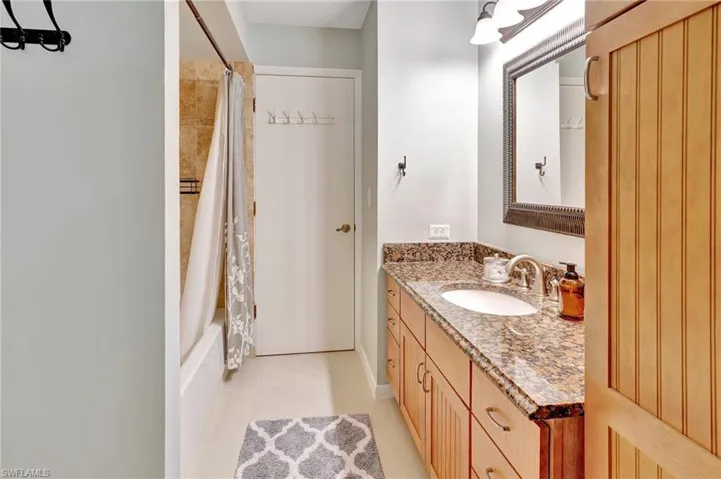 Bathroom with shower / bath combo with shower curtain, tile patterned flooring, and vanity