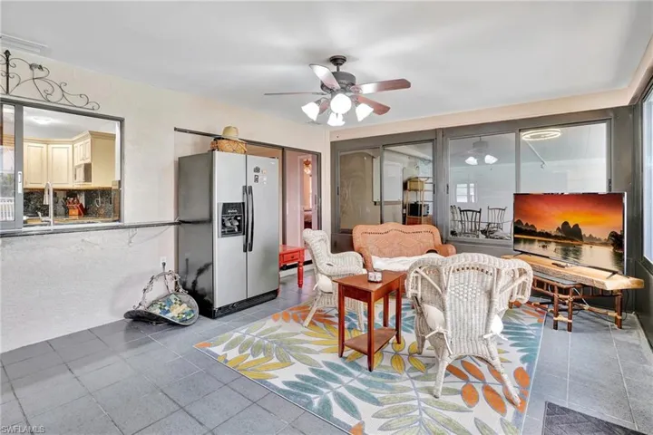 Living room with light tile patterned flooring, visible vents, and a ceiling fan