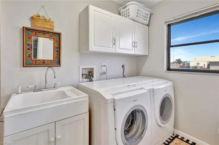Laundry room with cabinet space, separate washer and dryer, and a sink