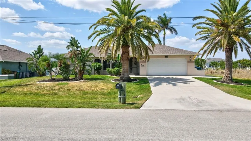 View of front facade with a garage, stucco siding, driveway, and a front yard