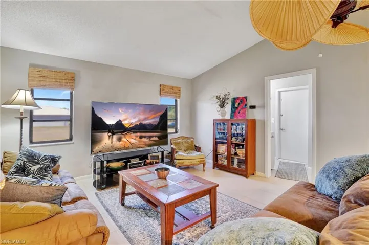 Living area featuring vaulted ceiling, tile patterned floors, and baseboards