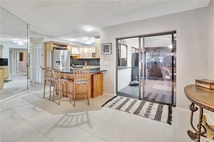 Kitchen featuring stainless steel refrigerator with ice dispenser, dark countertops, decorative backsplash, and a ceiling fan