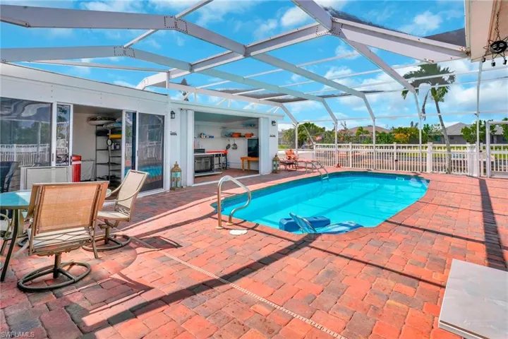 Pool with a patio, fence, and glass enclosure