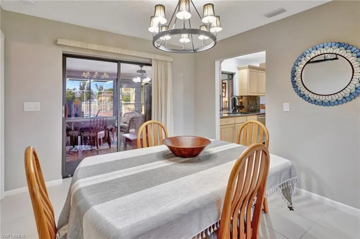 Dining room featuring light tile patterned flooring, a chandelier, visible vents, and baseboards