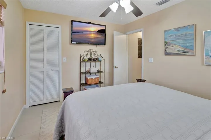Bedroom with light tile patterned flooring, a closet, a ceiling fan, visible vents, and baseboards