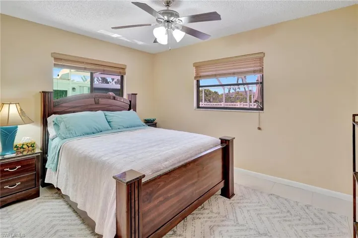 Bedroom featuring a textured ceiling, ceiling fan, light tile patterned flooring, and baseboards