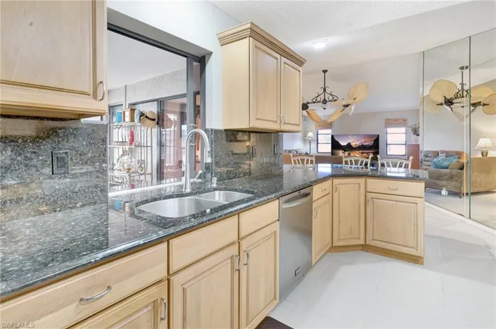 Kitchen featuring a sink, a chandelier, light brown cabinetry, stainless steel dishwasher, and open floor plan