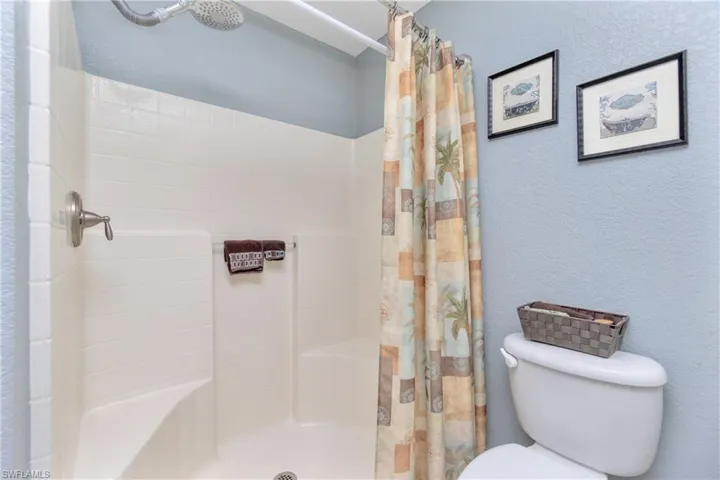 Bathroom with a textured wall, toilet, and a shower with shower curtain