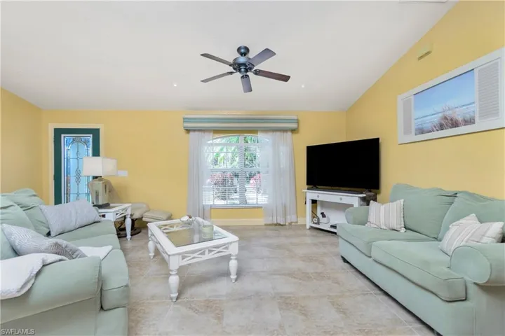 Living room with lofted ceiling, ceiling fan, and baseboards