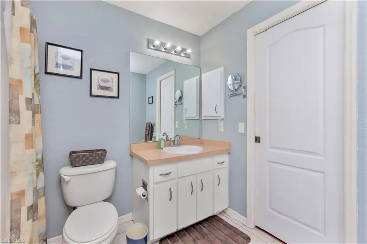 Full bath with a shower with curtain, baseboards, vanity, and toilet