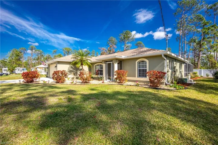 Single story home with an attached garage, a front lawn, and stucco siding