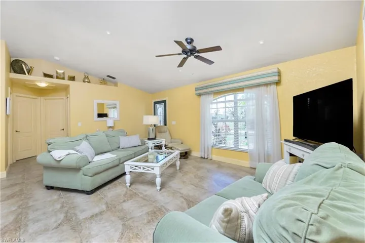 Living room featuring vaulted ceiling, baseboards, and ceiling fan